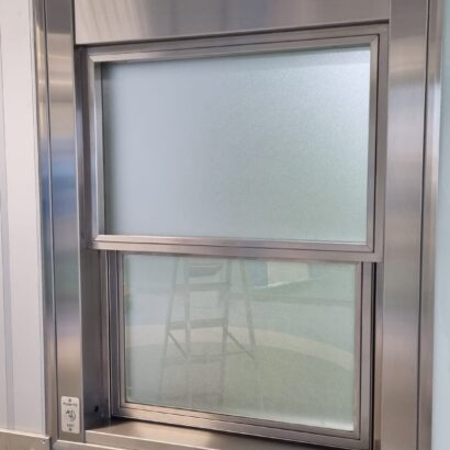 Ventana guillotina con apertura automatizada de ICMINOX instalada en quirófano, con vidrio plomado para protección de rediaciones y niveles de presión