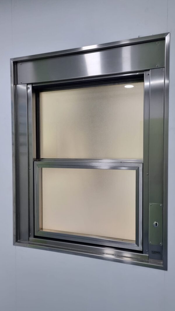 Ventana guillotina con apertura automatizada de ICMINOX instalada en quirófano, con vidrio plomado para protección de rediaciones y niveles de presión